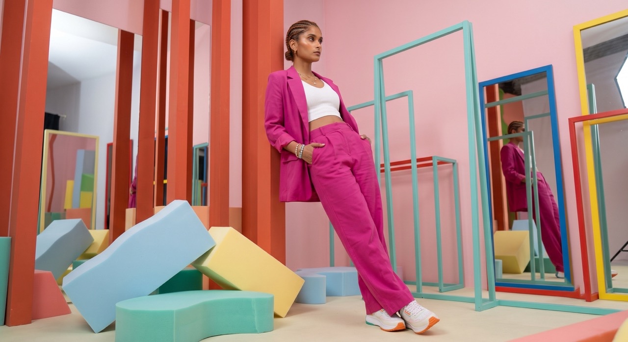 Confident Indian Woman Leaning in Pink Power Suit Studio | Royalty-Free image | Pixlaris