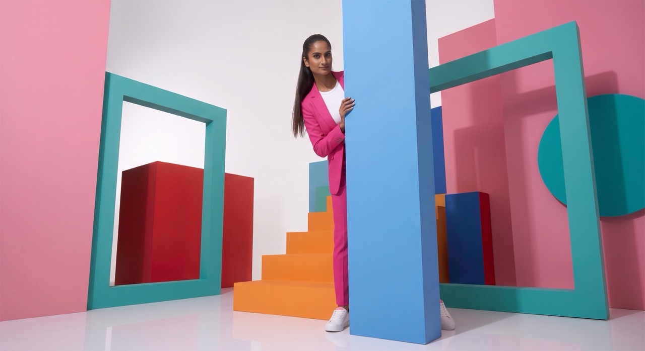 Playful Fashion Model Peeking Behind Blue Studio Pillar | Royalty-Free image | Pixlaris