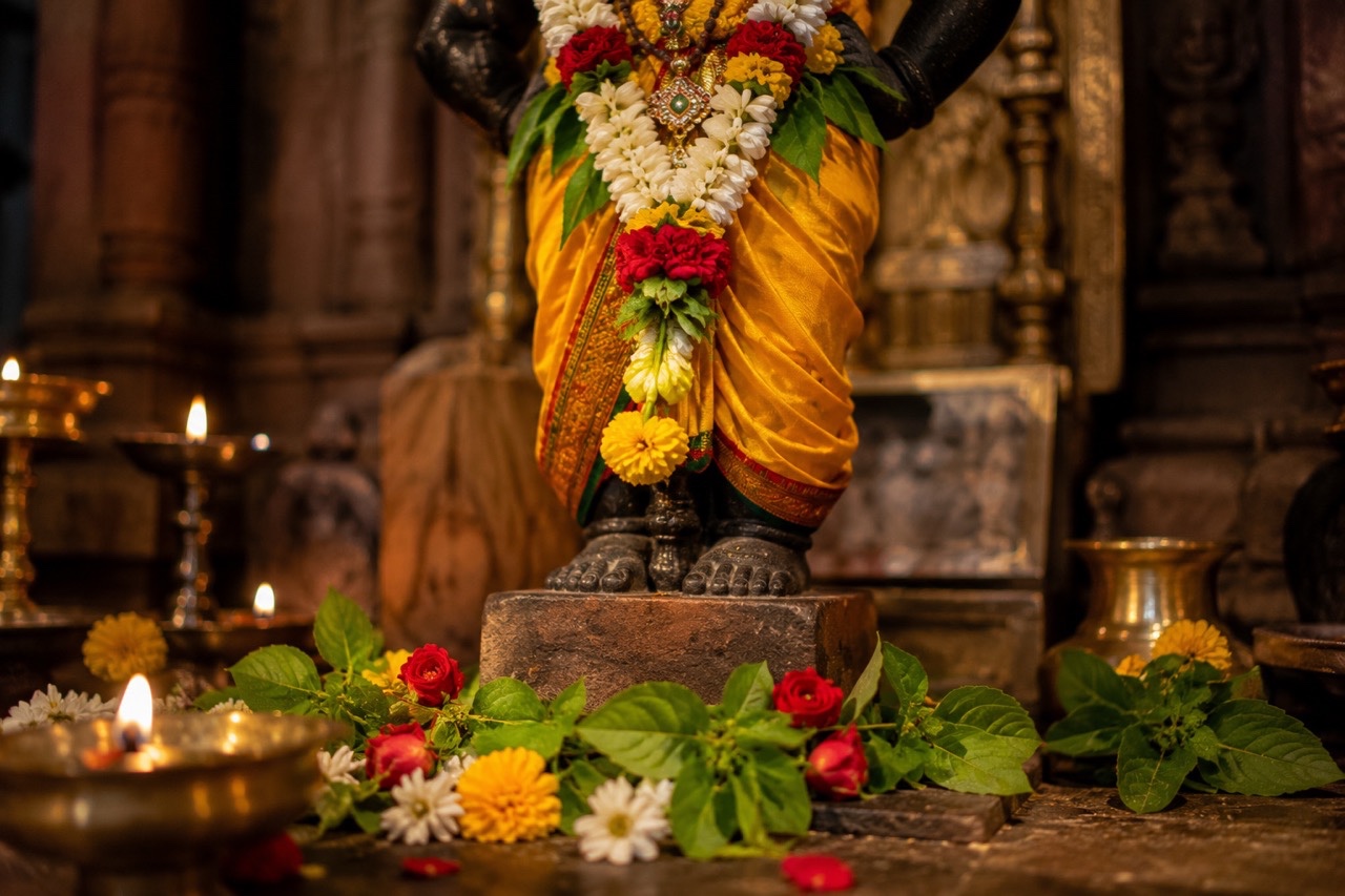 Close-Up of Vitthal Idol Feet with Flowers and Diyas | Royalty-Free image | Pixlaris